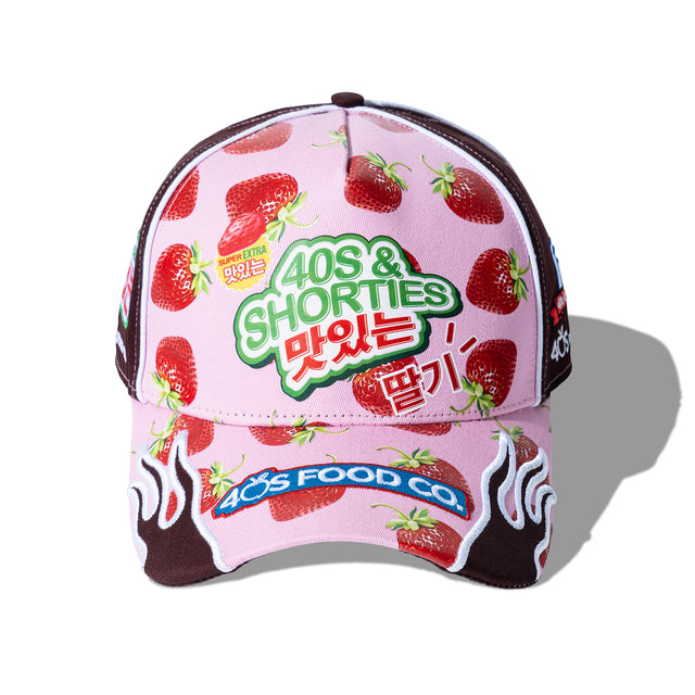 Angled view of Gummy Race Cap showing strawberry print, flame embroidery on the bill, and 40s & Shorties branding.