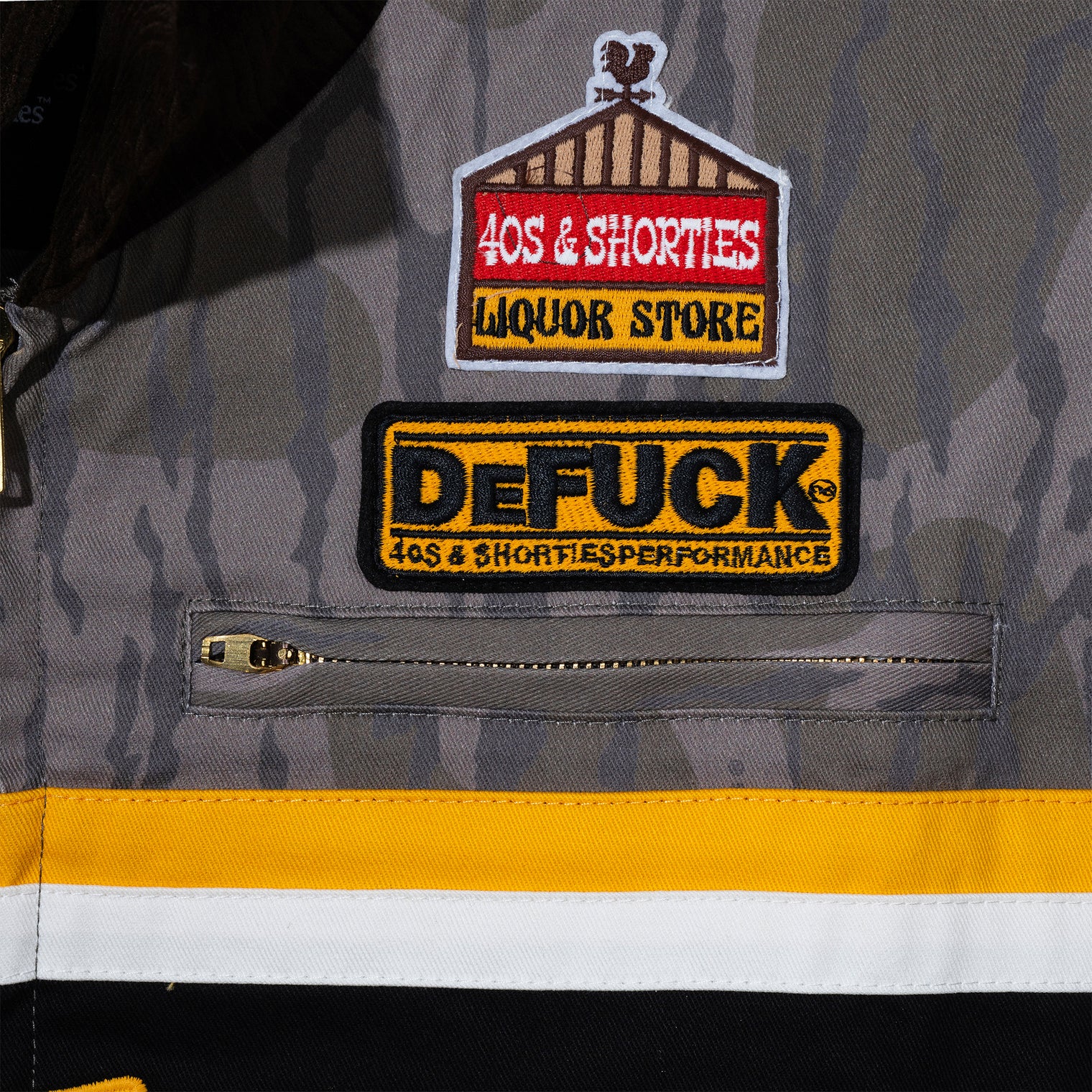 Zoomed-in view of Defuck patch and chest zip pocket on Camo Garage Jacket