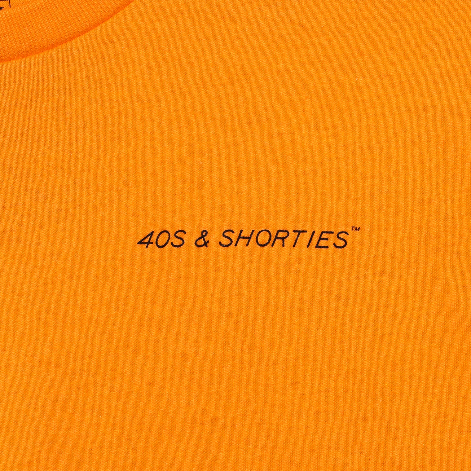 Close-up of front chest print on the Grid Tee Tangerine featuring "40s & Shorties" text in black.