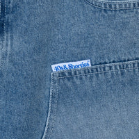 Close-up of 40s & Shorties woven label on front pocket of denim shorts.