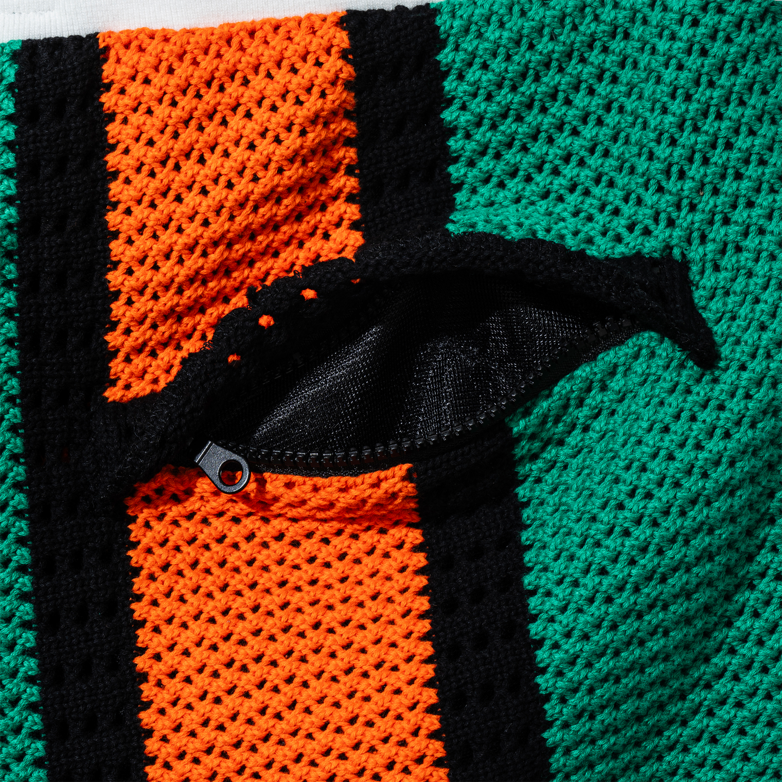 Close-up of zippered back pocket on Beachside Basketball Shorts showing black mesh lining and orange knit texture.