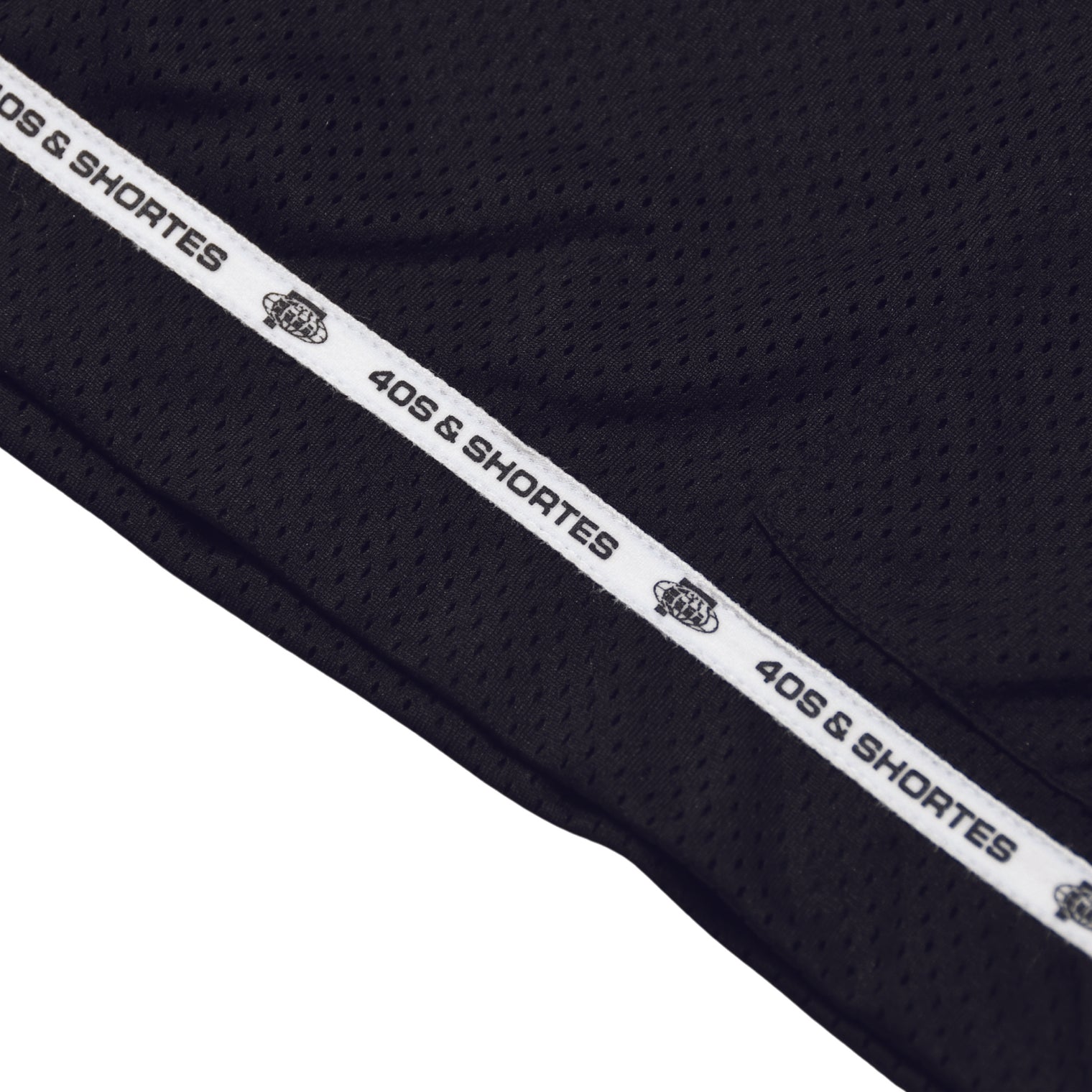 Detail shot of the custom logo hem taping at the bottom edge of the shorts.