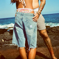 Rear view of model wearing the shorts outdoors, highlighting back pockets and frayed edges.