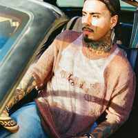 Lifestyle shot of model wearing the Fade Away Shirt in a car, sunlight revealing sheer texture.