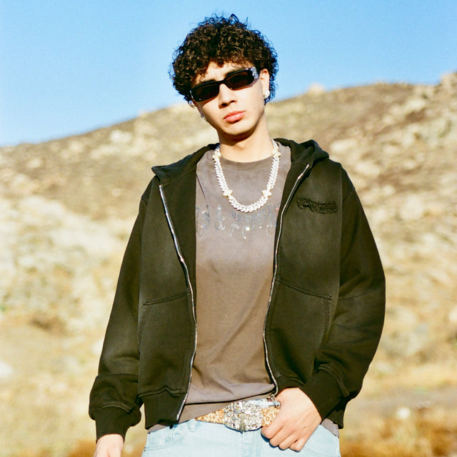 Model in 40s & Shorties Faded Logo Zip Hoodie black, standing in desert landscape.