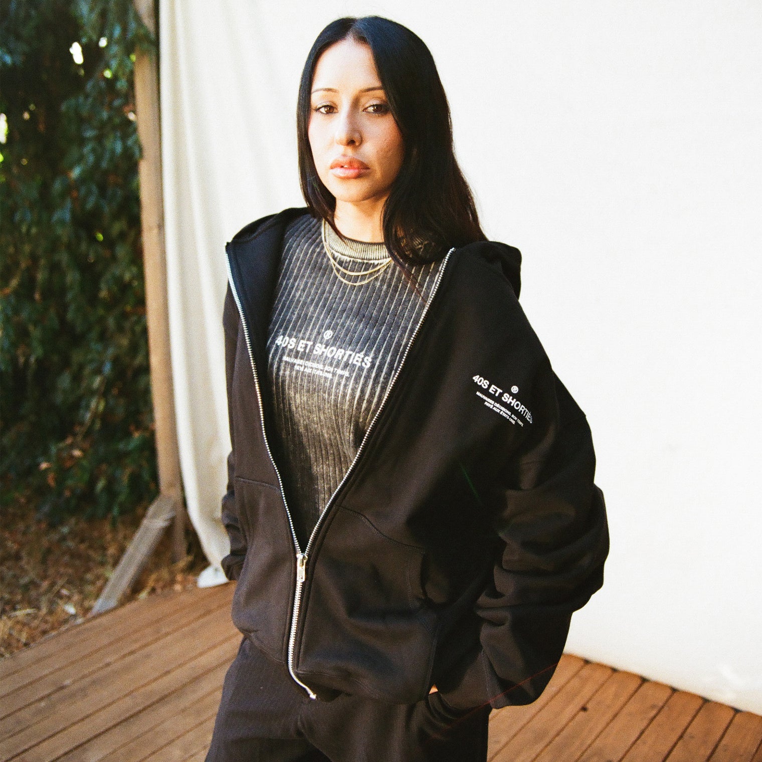 Female model wearing French General Zip Hoodie in black, layered over matching graphic tee – 40s & Shorties.