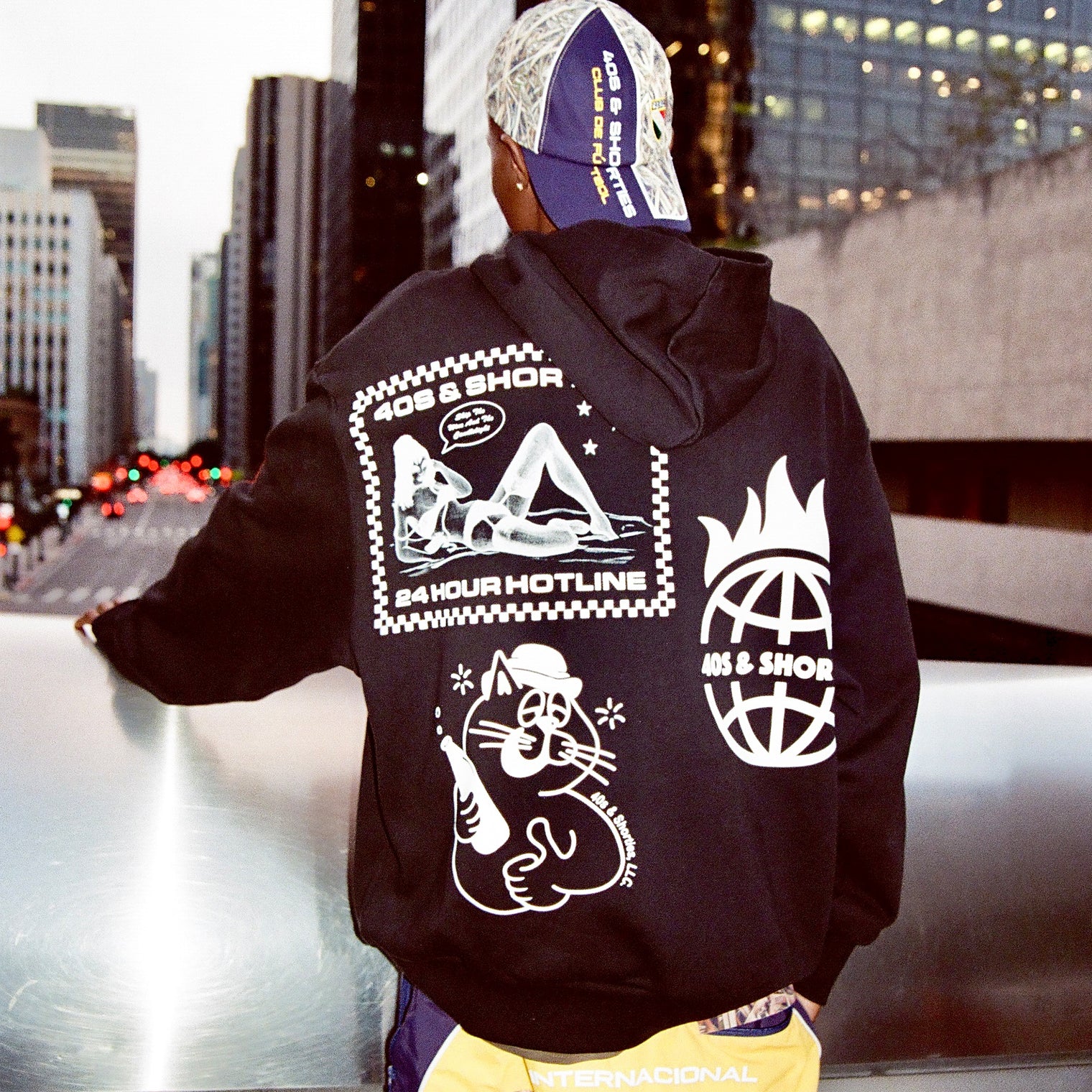 Back view of the hoodie worn by a model on a rooftop highlighting full back print graphics.