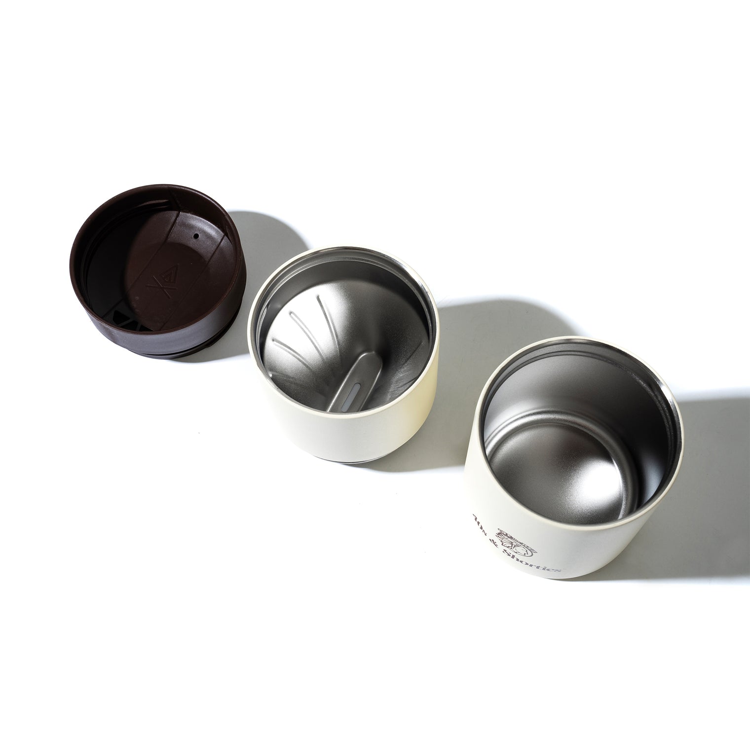 Top-down view of the Coffee Pour Over Set components, highlighting the brown lid, steel cone dripper, and stainless interior of the cream container.
