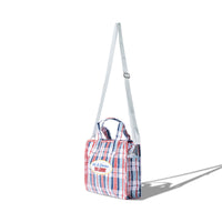 Angled side view of the Mini Laundry Bag showing white detachable shoulder strap and woven plaid fabric

