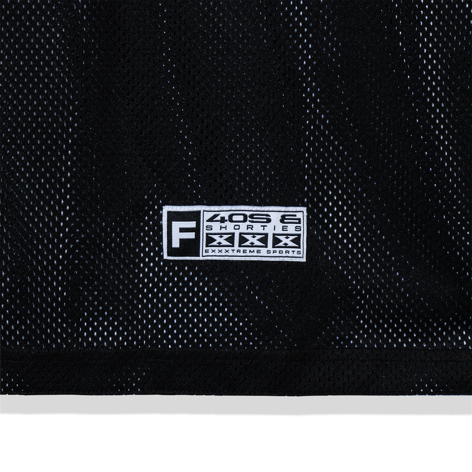 Close-up of woven patch near hem on the black mesh side
