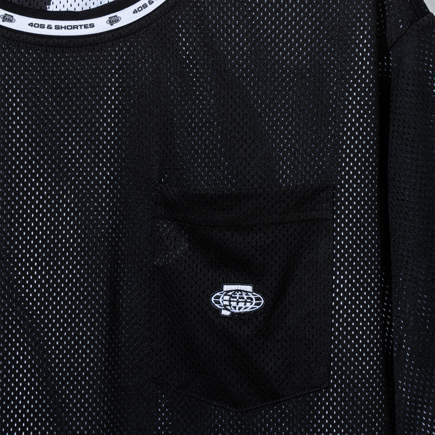 Close-up of chest pocket with globe embroidery on black mesh side
