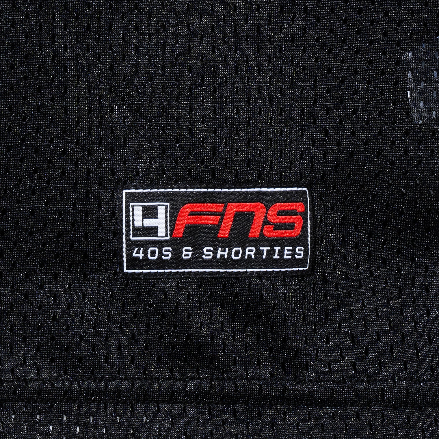 Detailed view of woven FNS logo label at the hem of the Fubar Jersey in Black.
