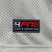 Detailed view of woven FNS logo label at the hem of the Fubar Jersey in Grey.
