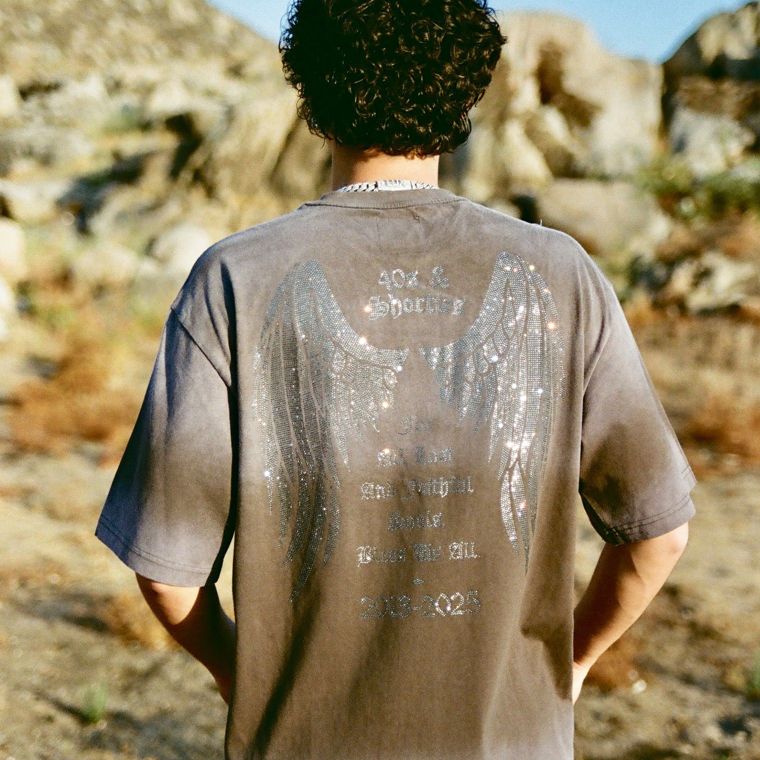 Back of 40s & Shorties Angel Wings Tee black featuring rhinestone angel wings and tribute text.
