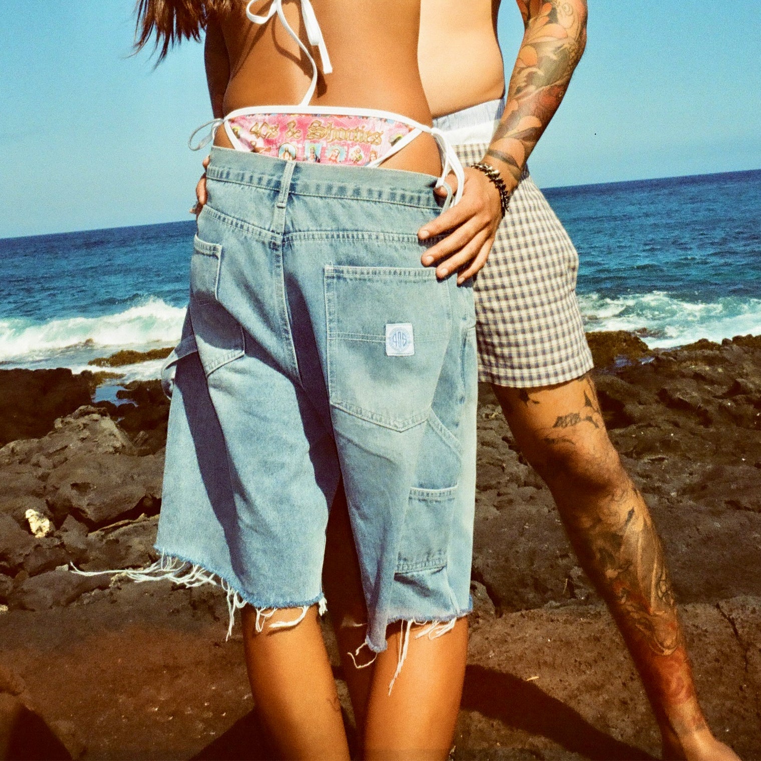 Rear view of model wearing the shorts outdoors, highlighting back pockets and frayed edges.
