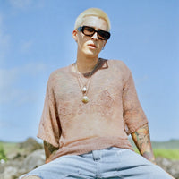 Model wearing Fade Away Shirt outdoors with layered necklaces and blue sky background.