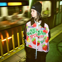 Model wearing Gummy Race Jacket in pink on a subway platform, styled with a beanie