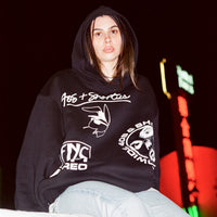 Night shot of a model in the Layout Hoodie with front graphics clearly visible against a city light backdrop.
