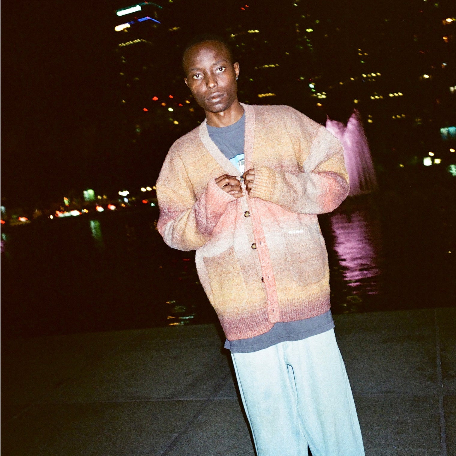 Model wearing the Lithium Cardigan by a fountain at night

