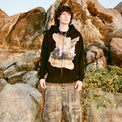 Model in 40s & Shorties Psycho Bunny Hoodie black with surreal bunny artwork standing against rocky backdrop.