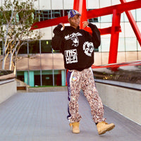 Lifestyle image of model wearing Reed Camo Track Pants outdoors