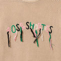 Close-up of hand-stitched 40s & Shorties logo with hanging loose threads in pink, green, white, and black