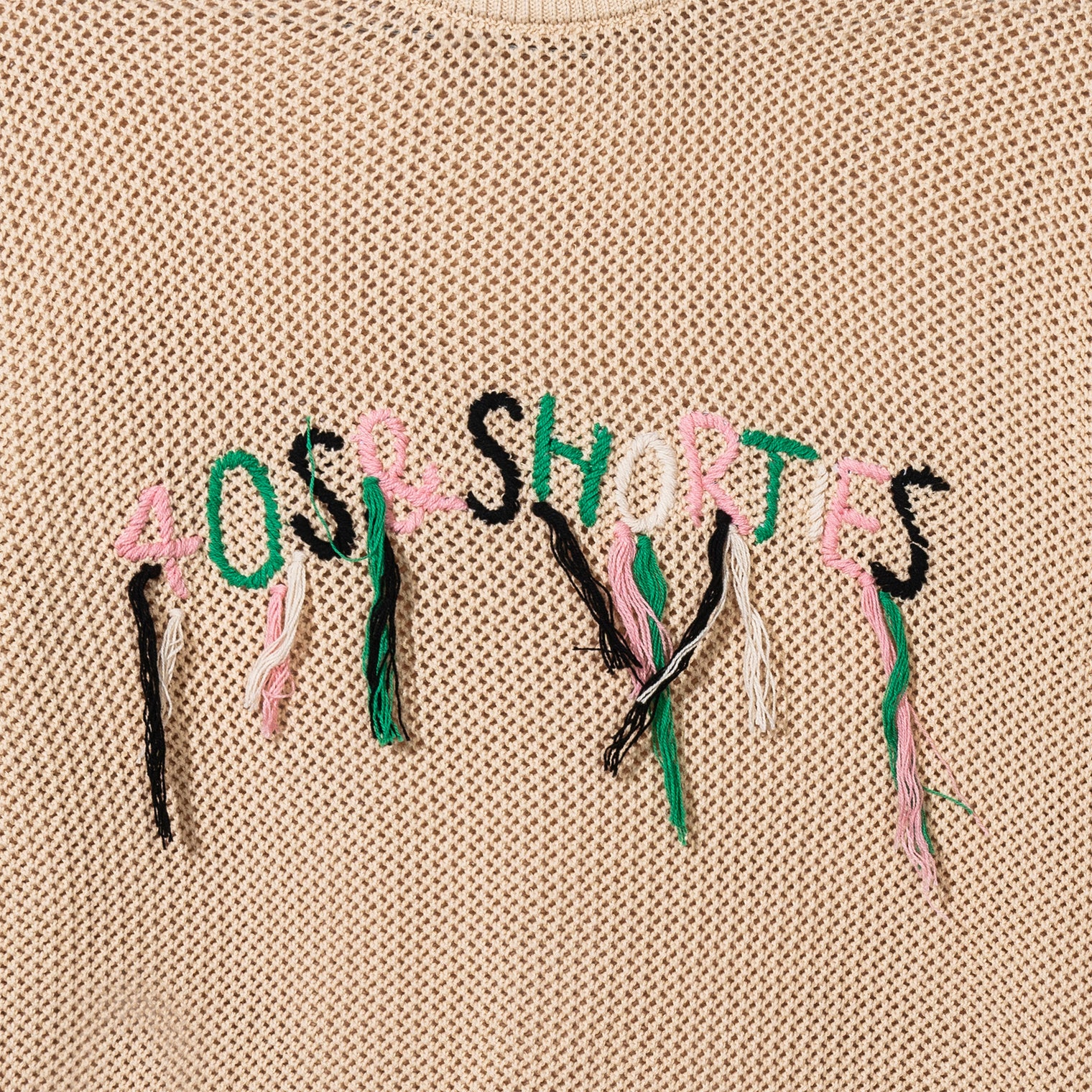Close-up of hand-stitched 40s & Shorties logo with hanging loose threads in pink, green, white, and black
