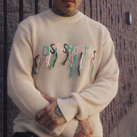 Model wearing the Scribble Logo Sweater in Cream with multicolored loose-thread logo across the chest